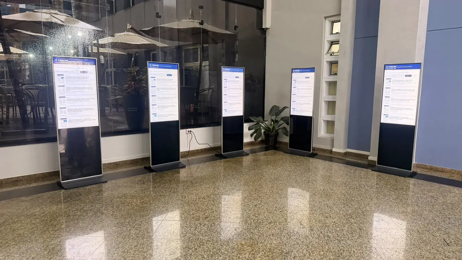 Área de pôsteres com cinco totens de e-pôster lado a lado